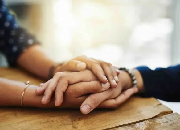Deux personnes se tenant la main en signe de soutien et de réconfort.