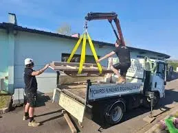 Ouvriers chargeant du matériel de marbrerie sur un camion avec une grue.