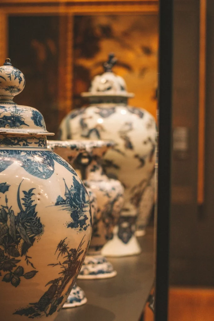 Vases en porcelaine blanche et bleue aux motifs asiatiques exposés en vitrine.