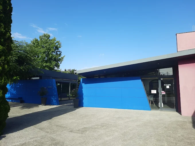 Entrée moderne d'une chambre funéraire aux murs bleus et roses sous un grand ciel bleu.